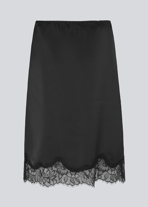 Black satin skirt with lace hem on a light gray background