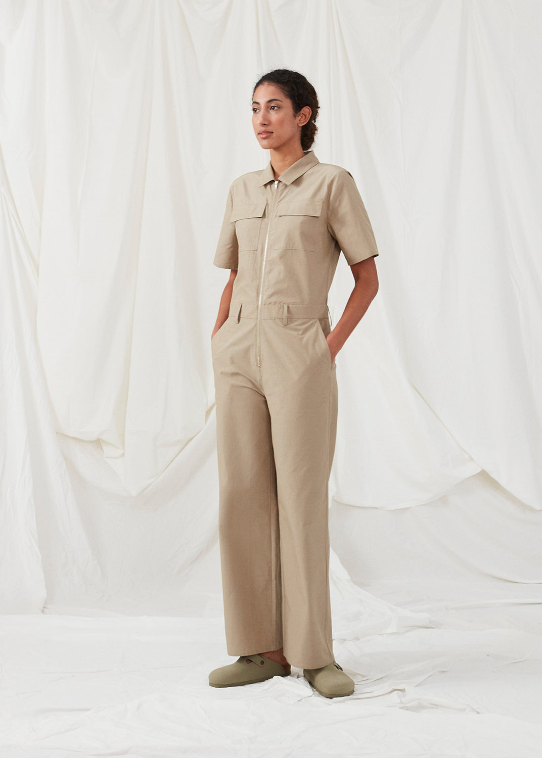 Jumpsuit in a crispy cotton blend with long, wide legs. DedeMD jumpsuit has short sleeves, collar, and zipper down the front. Belt straps at the waist. The model is 177 cm and wears a size S/36.