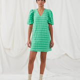 Short dress in green in a seersucker material. DinoMD dress has a v-shaped neckline, a loose silhouette, and short puff sleeves with elastic. The model is 177 cm and wears a size S/36.