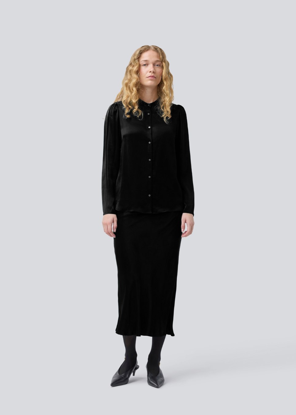 Black long wide satin skirt. Parveenmd skirt has an elastic waistband. The model is 175 cm and wears a size s/36.
