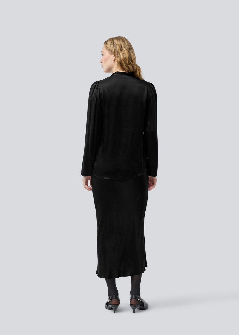 Black long wide satin skirt. Parveenmd skirt has an elastic waistband. The model is 175 cm and wears a size s/36.