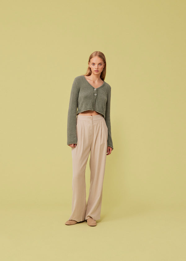 Cropped cardigan in soft green made from a fluffy material. HamptonMD cardigan has long sleeves, v-shaped neckline, and is closed with two buttons in front. 