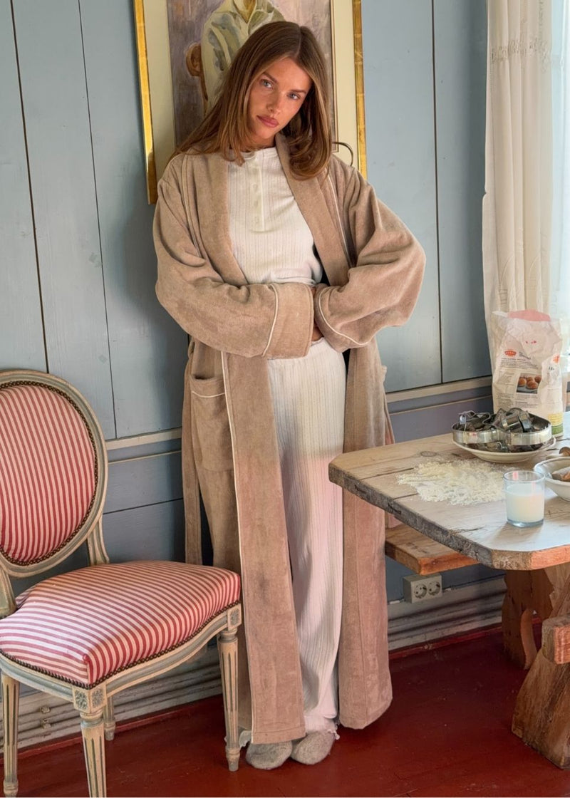 Beige oversized bathrobe. Josefinemd bathrobe is made from 100% organic cotton. It features large pockets, a belt, and contrast trims for an elegant touch. Finished with a subtle logo on the back – ideal for cozy mornings.&nbsp; Josefine Vogt (165 cm) and the model (177 cm) are both wearing size Small.