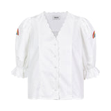 Bluse i sprød økologisk bomuld med pufærmer med brodering, knapper fortil og bølgede pyntekanter. PernilleMD shirt har v-formet udskæring og knapper langs forstykket.