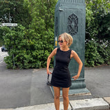 Fitted black mini dress in an A-line shape with a round neck and no sleeves. JosefineMD tank flare dress is made from a stretchy material. The model is 177 cm and wears a size S/36.