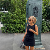 Fitted black mini dress in an A-line shape with a round neck and no sleeves. JosefineMD tank flare dress is made from a stretchy material. The model is 177 cm and wears a size S/36.