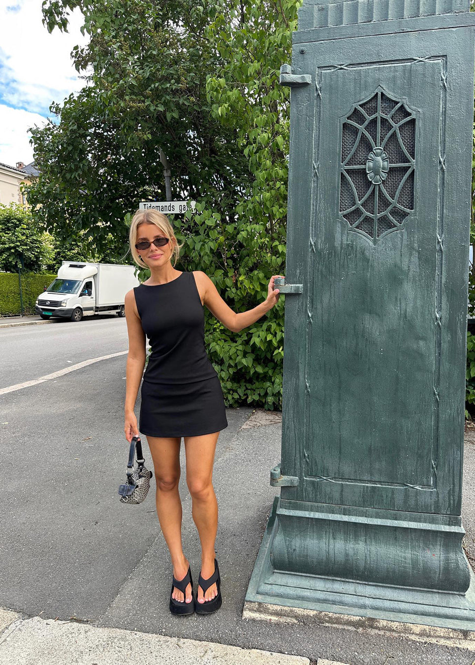 Fitted black mini dress in an A-line shape with a round neck and no sleeves. JosefineMD tank flare dress is made from a stretchy material. The model is 177 cm and wears a size S/36.