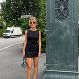 Fitted black mini dress in an A-line shape with a round neck and no sleeves. JosefineMD tank flare dress is made from a stretchy material. The model is 177 cm and wears a size S/36.