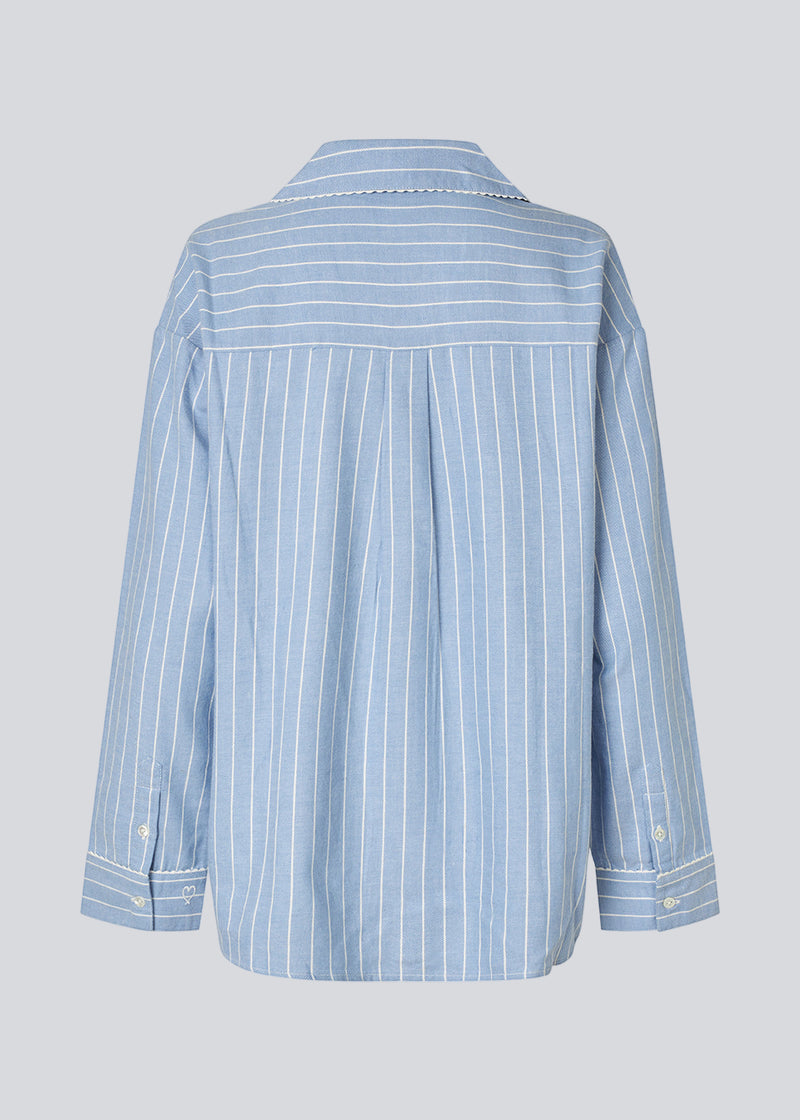 Blue classic striped pyjamas. The pyjamas is sold as a set of shirt and pants in the same size. Josefinemd pyjamas are made from 100% soft cotton and feature a classic fit with a collar, button closure, and drawstring trousers. Finished with delicate wave trim and comes with a matching pouch with logo. Josefine Vogt (165 cm) and the model (177 cm) are both wearing size Small.