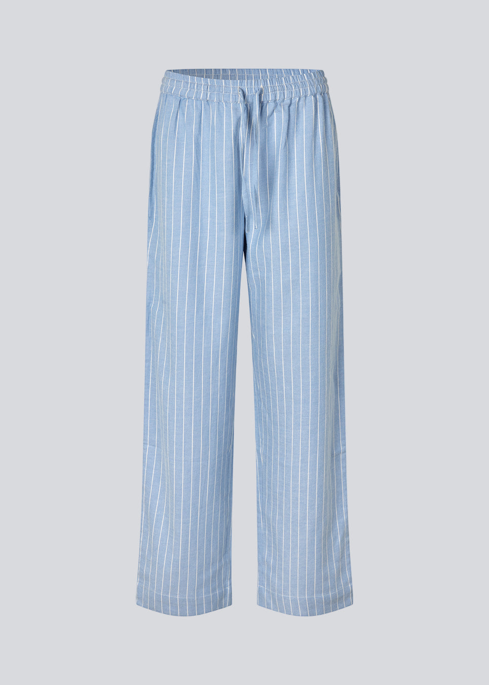 Blue classic striped pyjamas. The pyjamas is sold as a set of shirt and pants in the same size. Josefinemd pyjamas are made from 100% soft cotton and feature a classic fit with a collar, button closure, and drawstring trousers. Finished with delicate wave trim and comes with a matching pouch with logo. Josefine Vogt (165 cm) and the model (177 cm) are both wearing size Small.