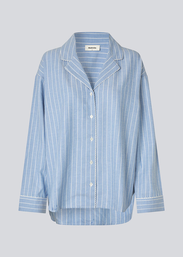 Blue classic striped pyjamas. The pyjamas is sold as a set of shirt and pants in the same size. Josefinemd pyjamas are made from 100% soft cotton and feature a classic fit with a collar, button closure, and drawstring trousers. Finished with delicate wave trim and comes with a matching pouch with logo. Josefine Vogt (165 cm) and the model (177 cm) are both wearing size Small.