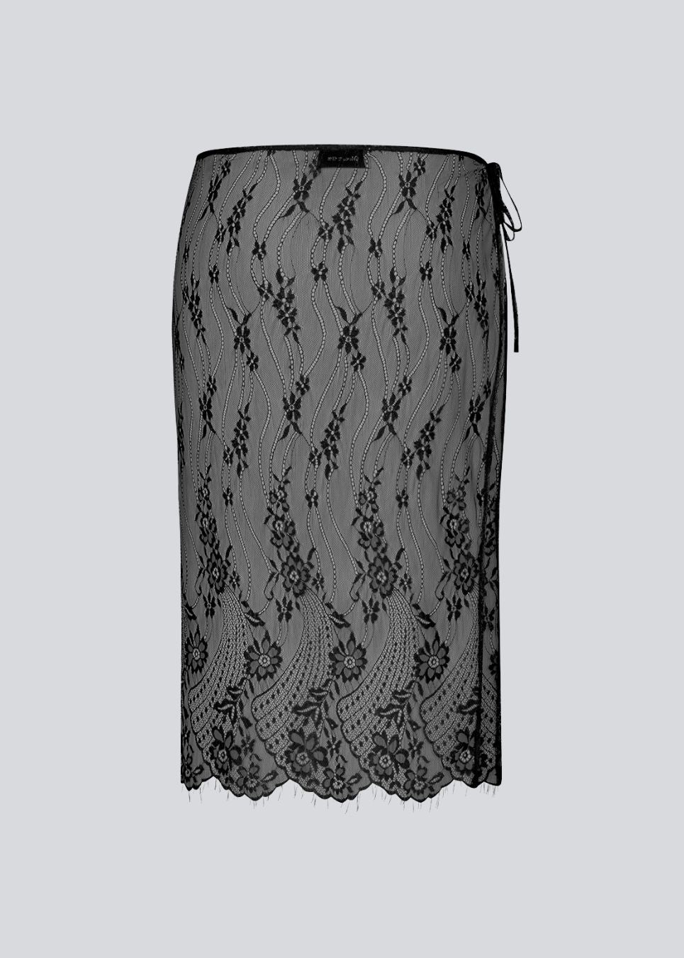 A square, sheer lace scarf worn as a wrap skirt. The Taffymd waist scarf ties at the side and is styled over trousers as part of the layered look trend.