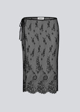 A square, sheer lace scarf worn as a wrap skirt. The Taffymd waist scarf ties at the side and is styled over trousers as part of the layered look trend.