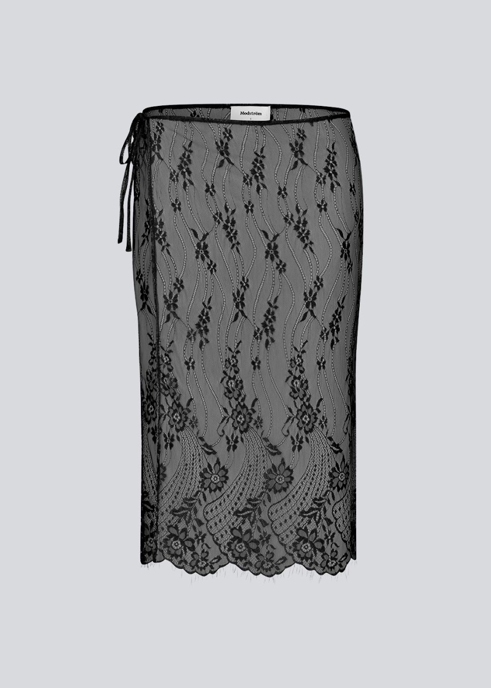 A square, sheer lace scarf worn as a wrap skirt. The Taffymd waist scarf ties at the side and is styled over trousers as part of the layered look trend.