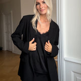 Satin top with a soft drape in black with black lace. TenjaMD top is detailed with lacing on the front and has thin straps.