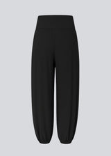 Balloon pants in black with a relaxed fit, made from 100% recycled polyester. Tullemd pants have an invisible side zipper, side pockets, and elastic at the leg hems.