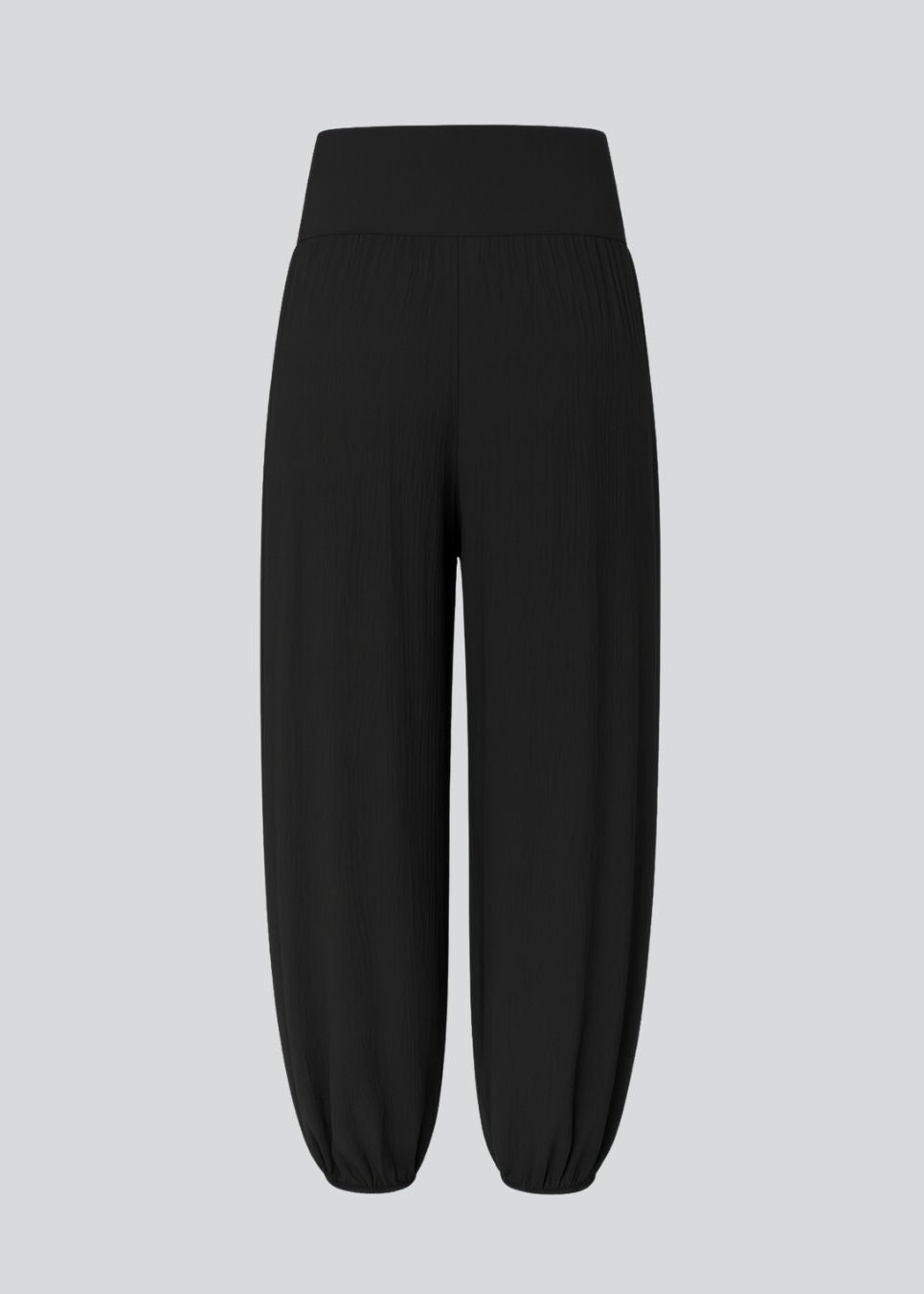 Balloon pants in black with a relaxed fit, made from 100% recycled polyester. Tullemd pants have an invisible side zipper, side pockets, and elastic at the leg hems.