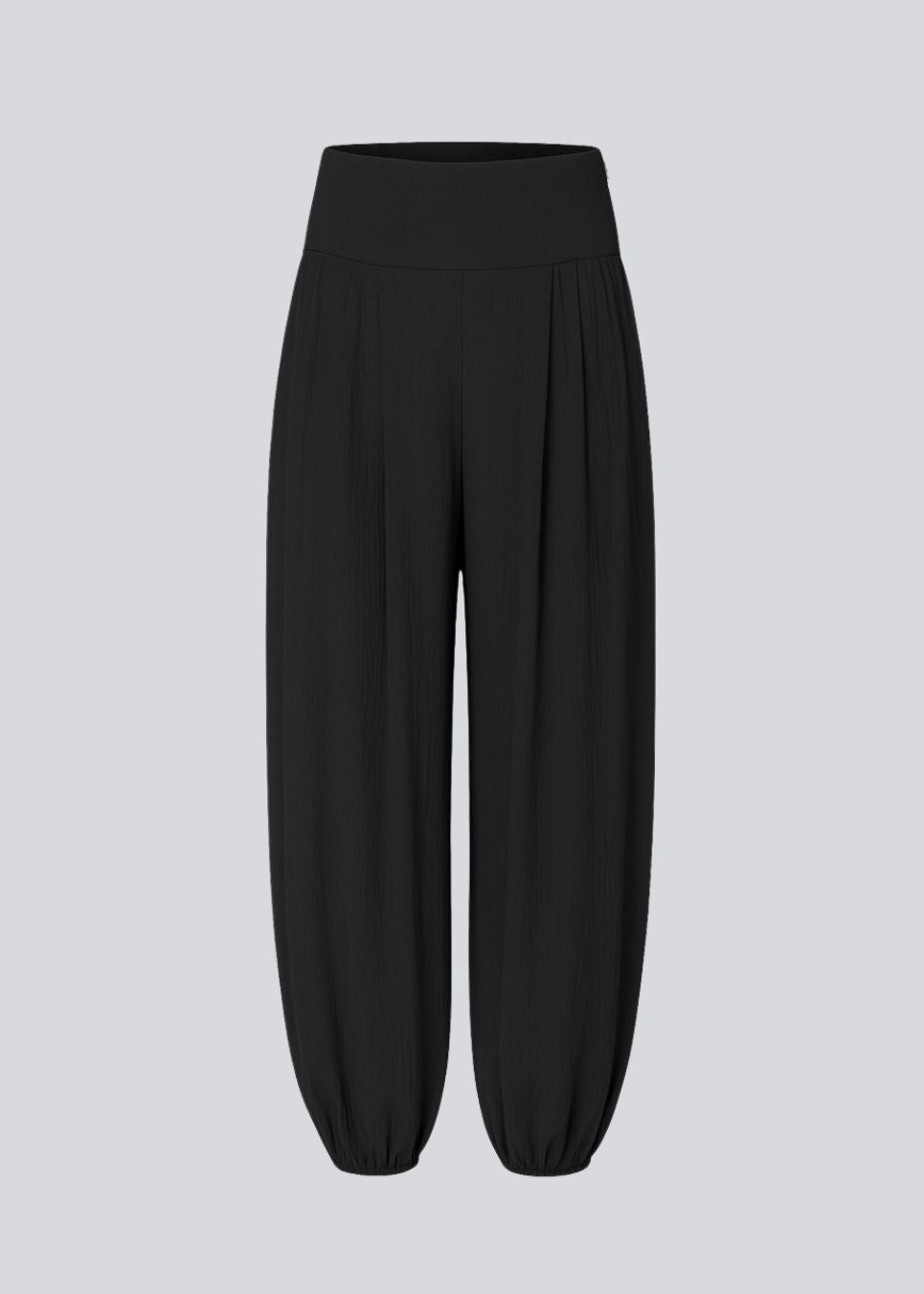 Balloon pants in black with a relaxed fit, made from 100% recycled polyester. Tullemd pants have an invisible side zipper, side pockets, and elastic at the leg hems.