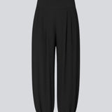 Balloon pants in black with a relaxed fit, made from 100% recycled polyester. Tullemd pants have an invisible side zipper, side pockets, and elastic at the leg hems.