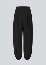 Balloon pants in black with a relaxed fit, made from 100% recycled polyester. Tullemd pants have an invisible side zipper, side pockets, and elastic at the leg hems.