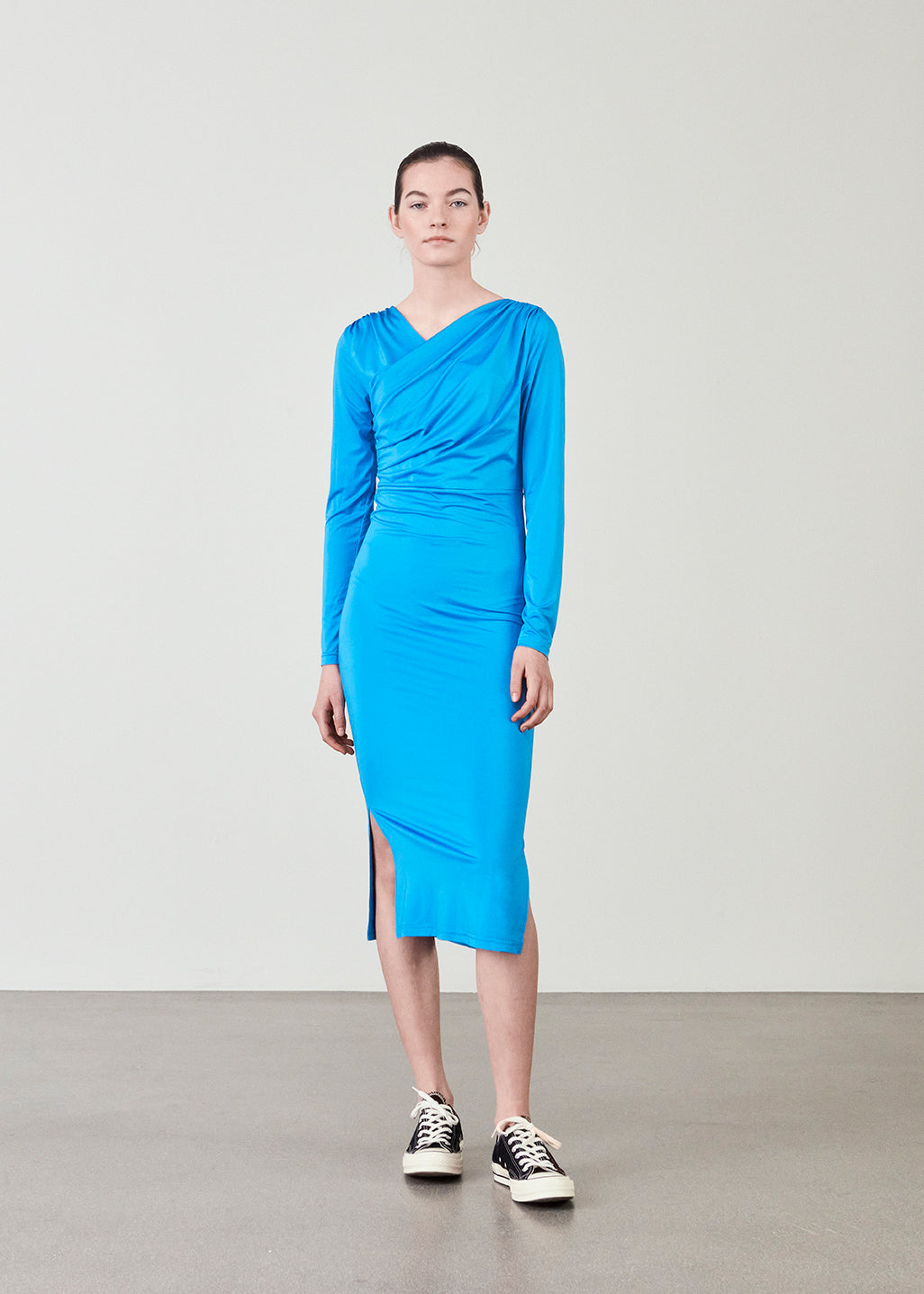 Form-fitted dress in blue with long skirt with slits at both sides. ArniMD dress has a high v-neckline med flattering wrap detail over the chest.