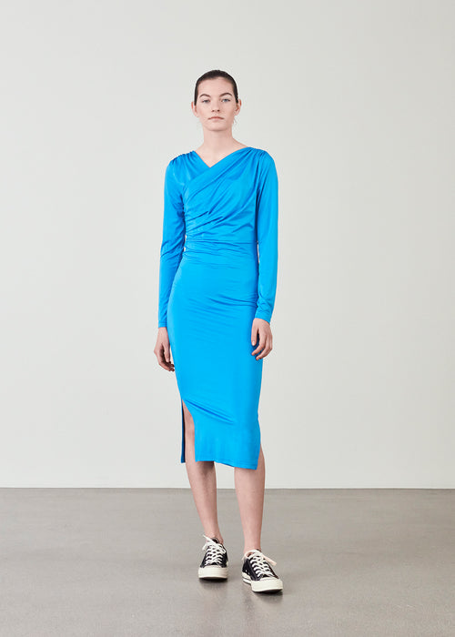 Form-fitted dress in blue with long skirt with slits at both sides. ArniMD dress has a high v-neckline med flattering wrap detail over the chest.