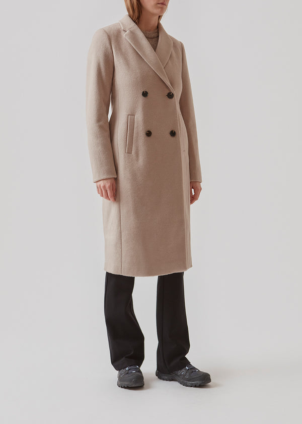 Beautiful, long woolen coat in grey. Odelia long coat is double-breasted and slightly fitted at the waist for a feminine expression. The coat is an obvious choice for both fall and mild winters.