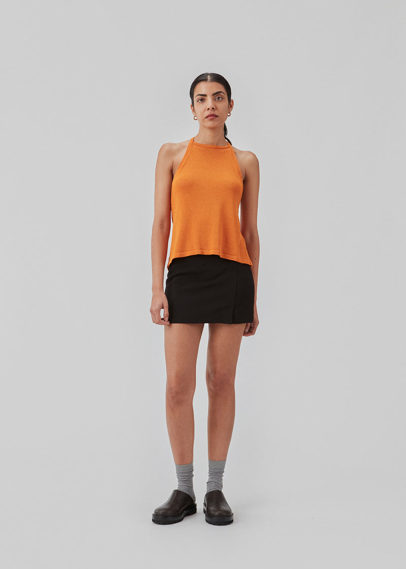 Halterneck top in a knitted material with a soft drape. JosefineMD halterneck top has a high neck in the front and an open back with ties at the neck and waist. The model is 177 cm and wears a size S/36.