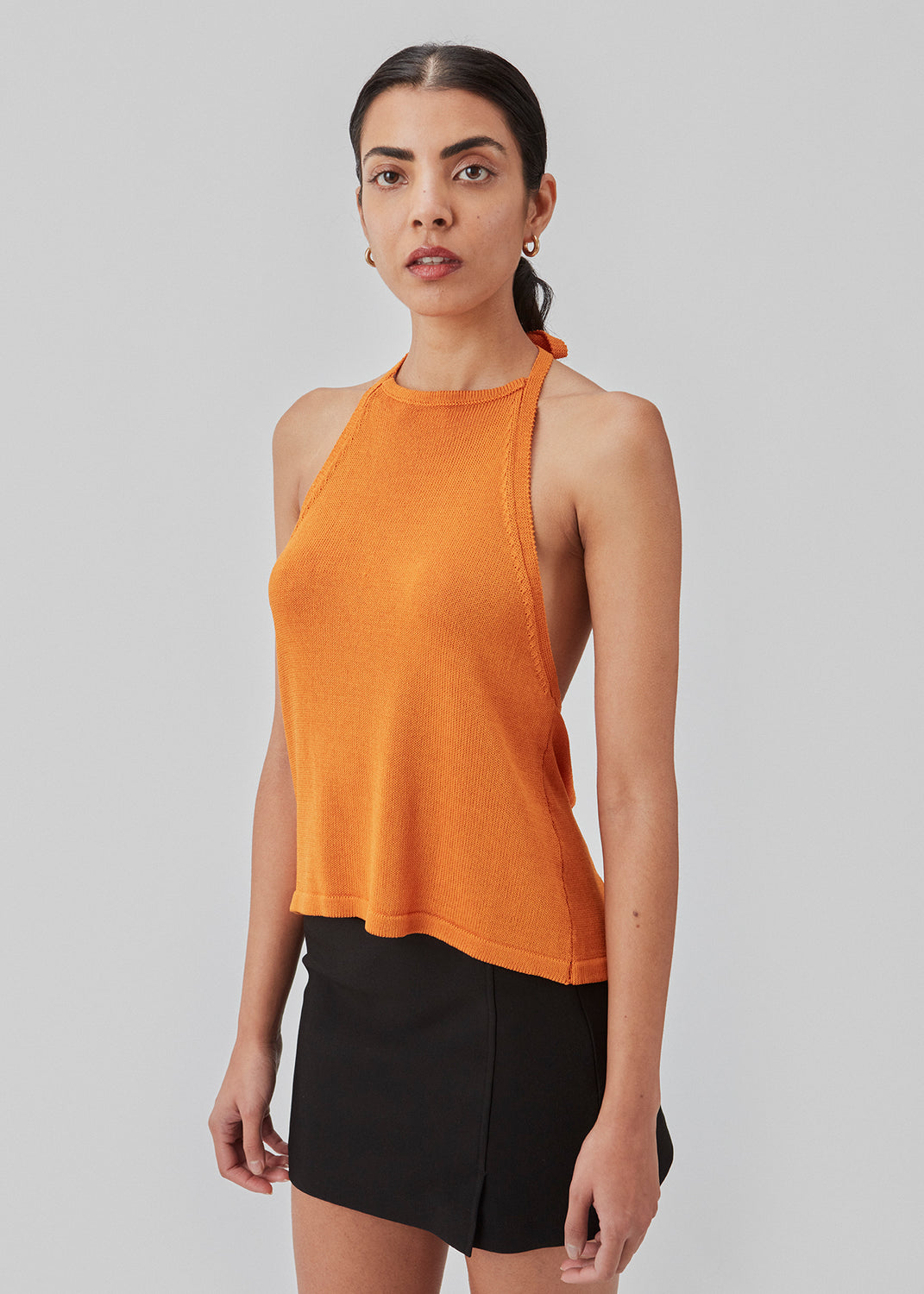 Halterneck top in a knitted material with a soft drape. JosefineMD halterneck top has a high neck in the front and an open back with ties at the neck and waist. The model is 177 cm and wears a size S/36.