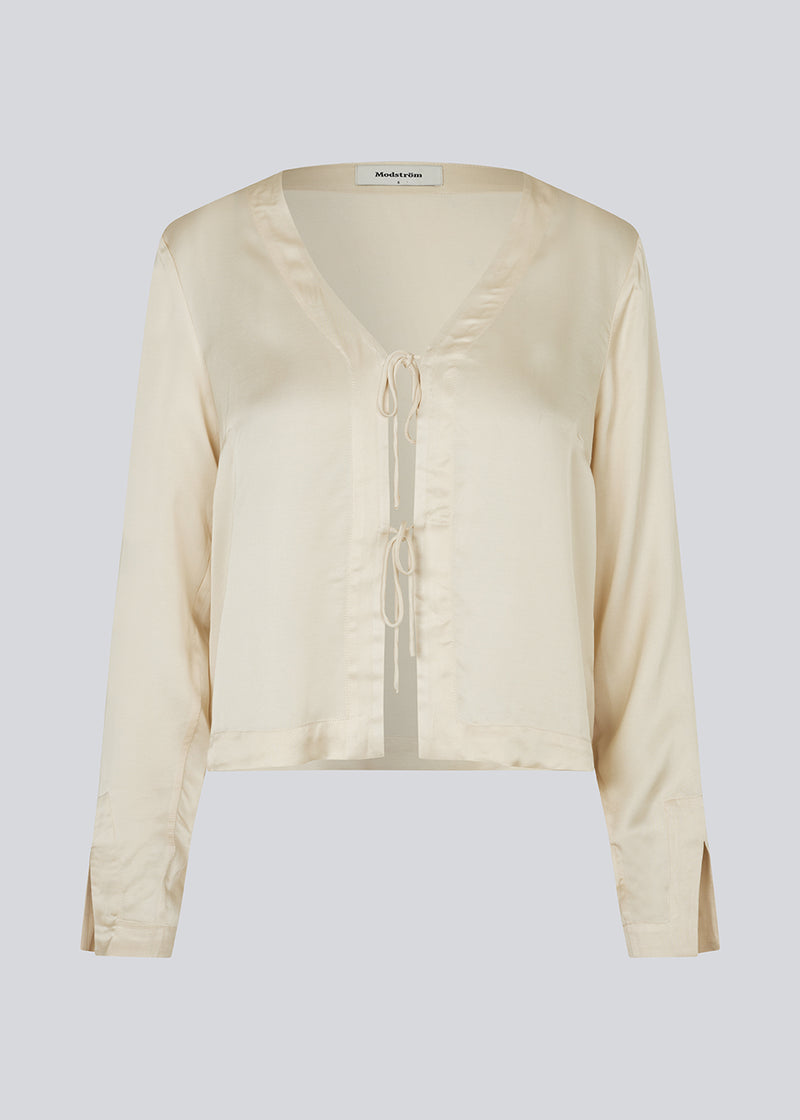 TulaMD shirt in an EcoVero viscose. The shirt is designed with a v-shape at the neckline, opening in front with tie, and long sleeves with a slit. 