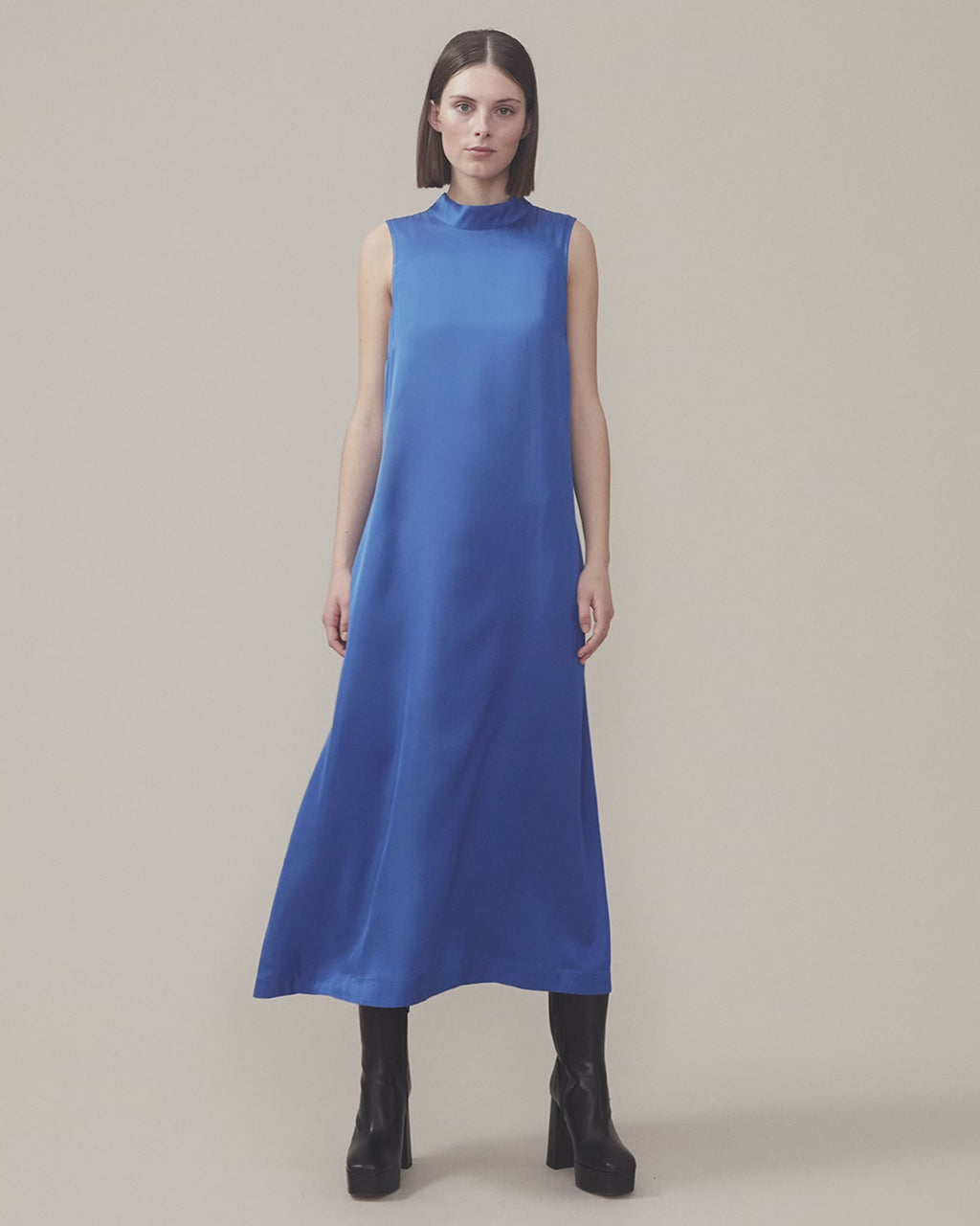 Long dress with a high neck in a softly draping more responsible satin quality. BeateMD dress is sleevesless and with a small opening in the neck with a discreet button closure.