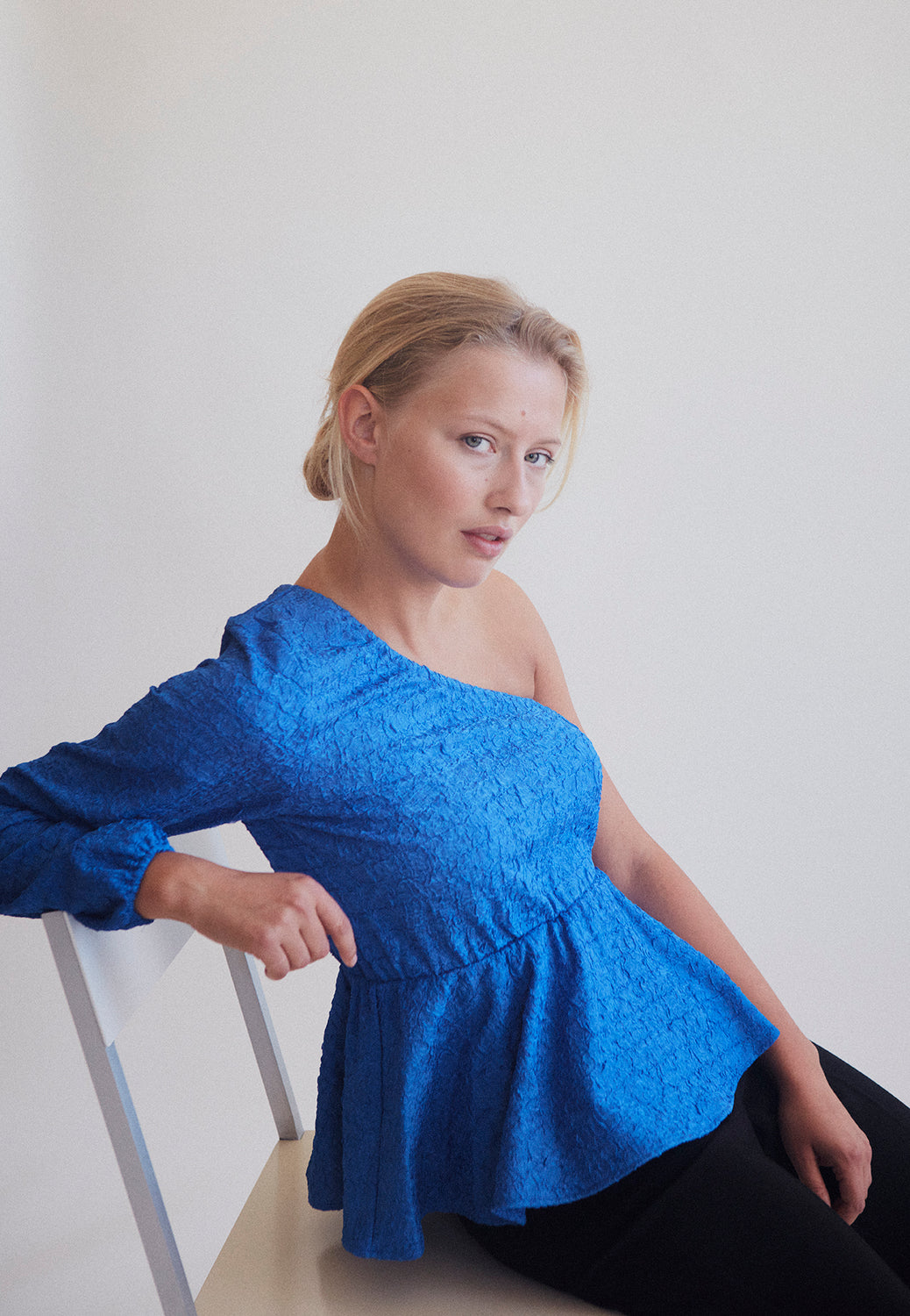 One shoulder top med et langt ærmer med puf og elastisk manchet. TalissaMD top er designet i et struktureret materiale med elastisk peplum-effekt ved taljen.