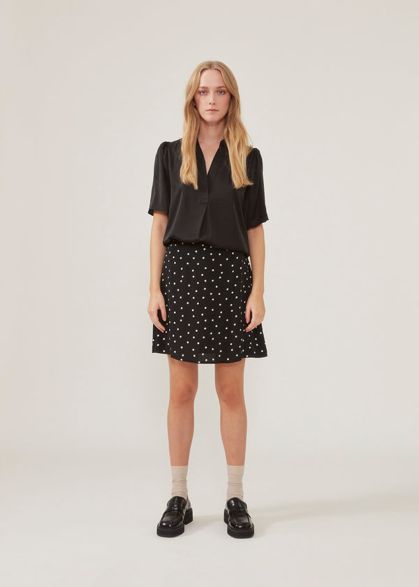 High-waisted mini skirt in black in a dotted EcoVero viscose with an airy fit. Covered elasticated waist on the back and a smooth back. The model is 173 cm and wears a size S/36
