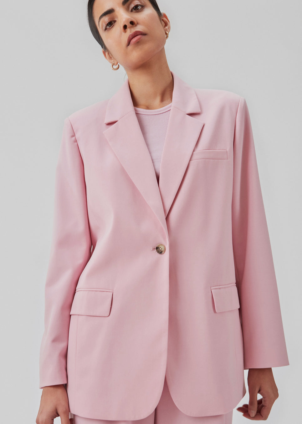 Oversized blazer in dusty sorbet with a drapey fit. AnkerMD blazer has collar and notch lapels with a single button closure. Flap welt front pockets. Slits on cuffs and single back vent. Lined.  The model is 177 cm and wears a size S/36.