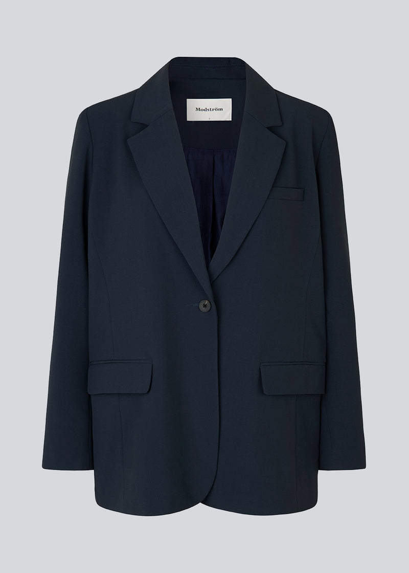 Oversized blazer in navy blue with a drapey fit. AnkerMD blazer has collar and notch lapels with a single button closure. Flap welt front pockets. Slits on cuffs and single back vent. Lined. The model is 177 cm and wears a size S/36.  Match with: AnkerMD wide pants or AnkerMD slit pants.