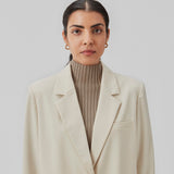 Oversized blazer in beige with a drapy fit. AnkerMD blazer has collar and notch lapels with a single button closure. Flap welt front pockets. Slits on cuffs and single back vent. Lined.  The model is 177 cm and wears a size S/36.  Shop matching shorts: AnkerMD shorts or bukser: AnkerMD pants.