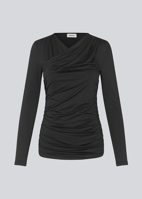 Long sleeved top in black with a formfitted shape and in a stretchy material. ArniMD top has a high v-neckline with a wrap-effect in front.