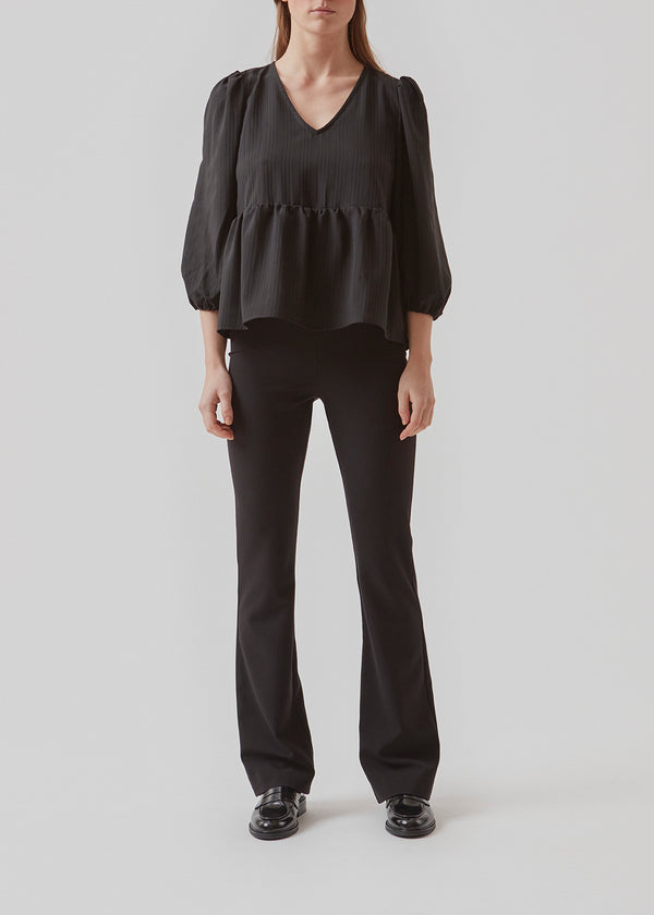 Top in black in a loose silhouette with 3/4 length sleeves, v-shaped neckline and a cutline at the waist for extra volume on the bottom of the top.  Material: 100% Polyester