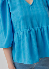 Top in blue in a loose silhouette with 3/4 length sleeves, v-shaped neckline and a cutline at the waist for extra volume on the bottom of the top.  Material: 100% Polyester