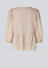 Top in beige in a loose silhouette with 3/4 length sleeves, v-shaped neckline and a cutline at the waist for ekstra volume on the bottom of the top.
