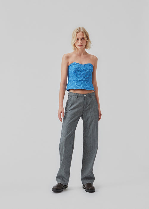 Crop top in blue without sleeves with a heart-shaped neckline and a slight peplum-effect. AtiraMD crop top has a structured floral pattern.  The model is 177 cm and wears a size S/36.