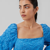 Short dress in blue with all-over floral structure. AtiraMD dress has long balloon sleeves and a more fitted body. The neckline is square in front and back.  The model is 177 cm and wears a size S/36.