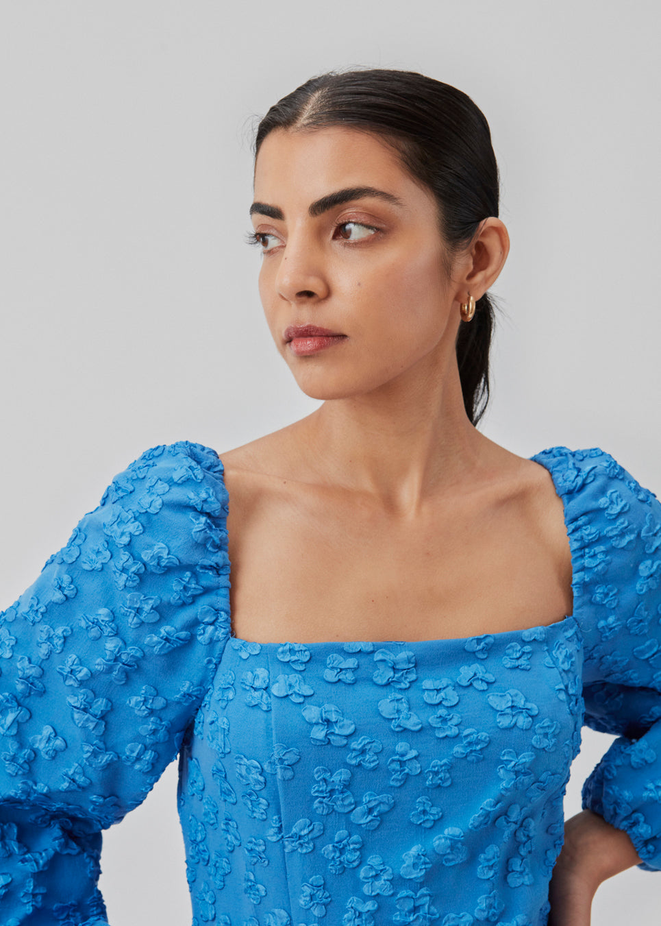 Short dress in blue with all-over floral structure. AtiraMD dress has long balloon sleeves and a more fitted body. The neckline is square in front and back.  The model is 177 cm and wears a size S/36.