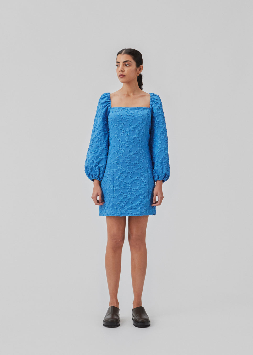 Short dress in blue with all-over floral structure. AtiraMD dress has long balloon sleeves and a more fitted body. The neckline is square in front and back.  The model is 177 cm and wears a size S/36.