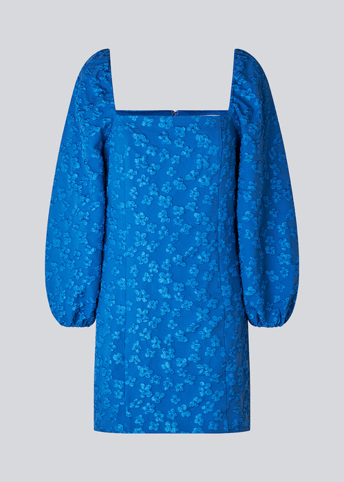Short dress in blue with all-over floral structure. AtiraMD dress has long balloon sleeves and a more fitted body. The neckline is square in front and back.  The model is 177 cm and wears a size S/36.