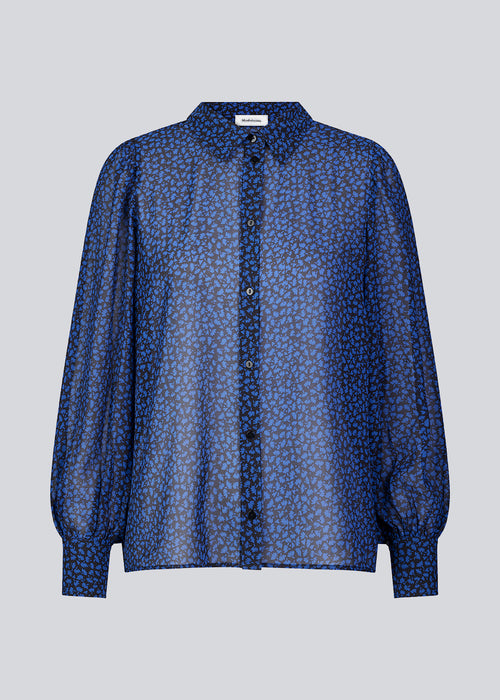 Shirt in blue in a light quality from recycled materials. BaoMD print shirt has long balloon sleeves with cuff, collar, and button closure in front. The shirt is slightly see-through.