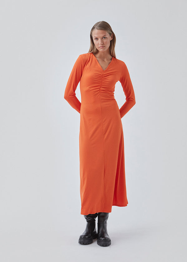 Tight dress in orange in stretchable quality and A shape. BartoMD dress has long sleeves and V-neckline with wrinkle detail at the waist.