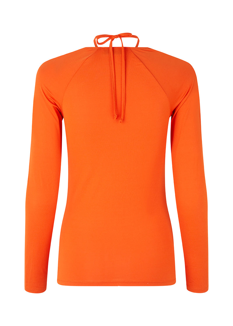 Long sleeved top in orange in a tight fit. BartoMD has a squared neckline with adjustable halterneck bow that can be tied at the neck.