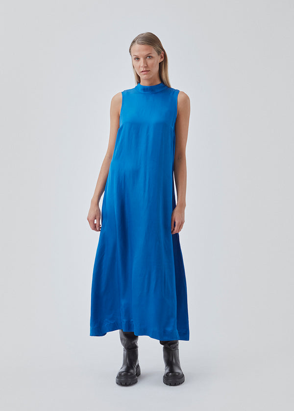 Long dress with a high neck in a softly draping more responsible satin quality. BeateMD dress is sleevesless and with a small opening in the neck with a discreet button closure.