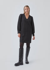 Minidress in black with long volume sleeves and a cuff. BisouMD dress has a v-neckline and an a-shaped silhouette in the body